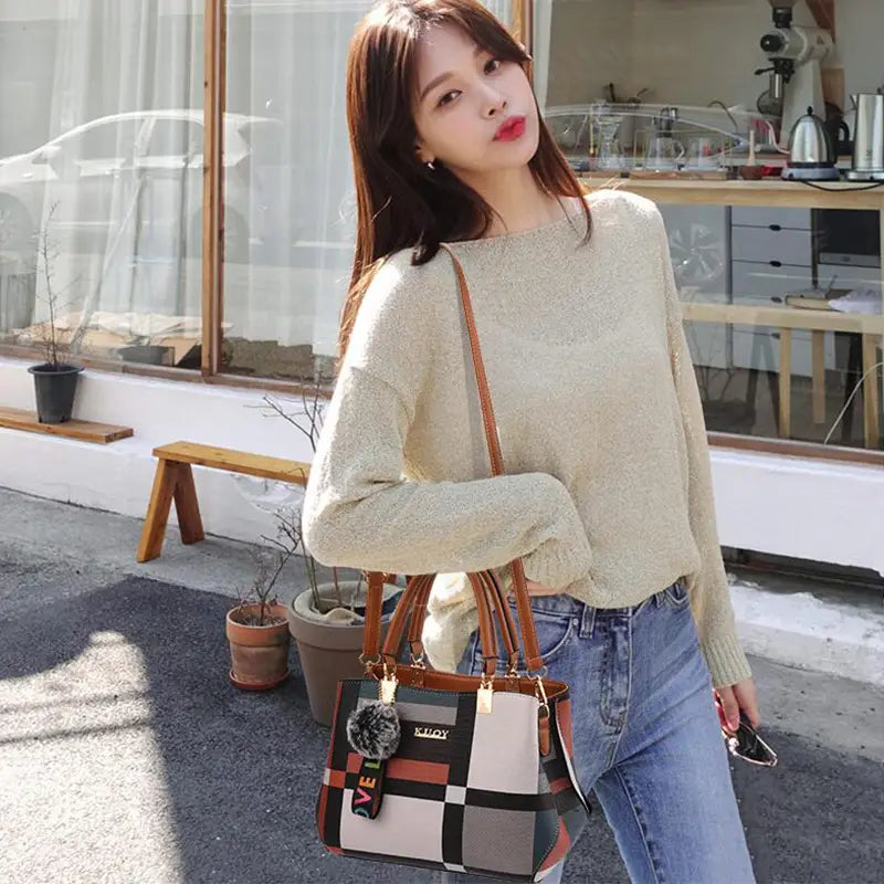 A stylish black crossbody handbag in style1 style2 made of pu leather featuring checkered design brown leather straps and a decorative pom-pom charm.