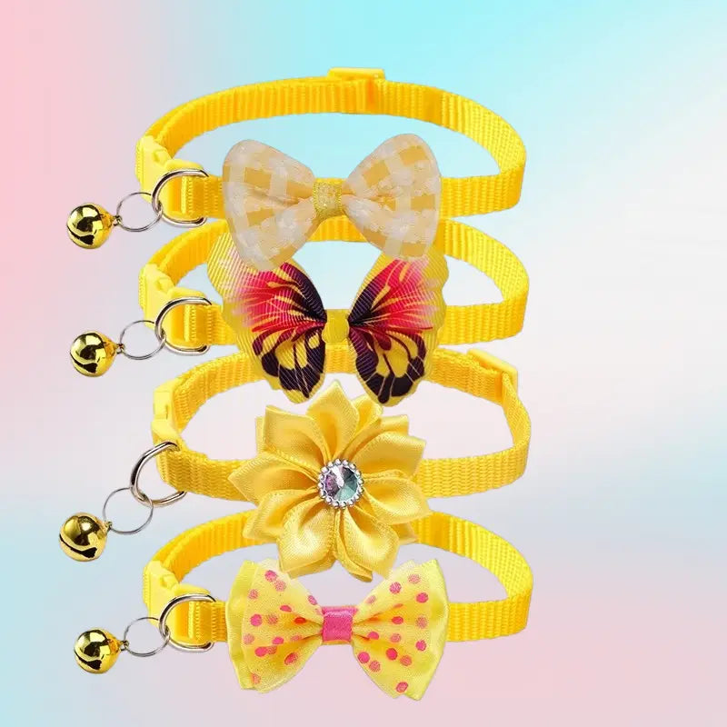Set of four adjustable bright yellow cat collars with small golden bells each adorned with unique decorative bow or flower charms.