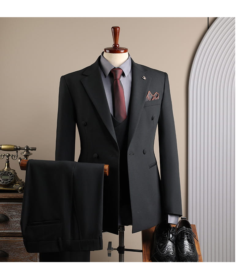 Veste de costume d’affaires pour homme noire slim fit à double boutonnage, avec revers crantés, portée sur un gilet assorti et une chemise habillée gris clair, adaptée aux soirées décontractées et aux occasions d’affaires en mode masculine.