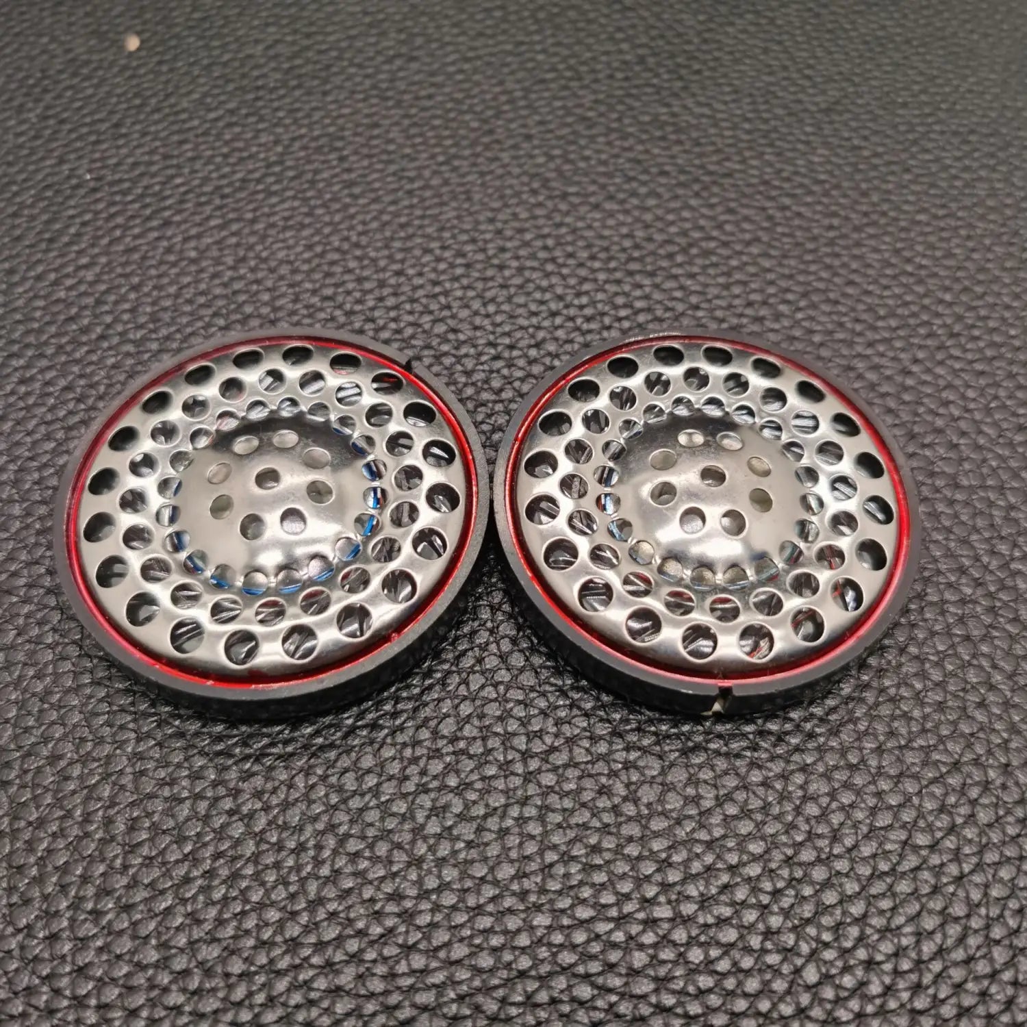 Dos altavoces circulares metálicos de repuesto para auriculares Ath-ad900x con diseño perforado y bordes con borde rojo.