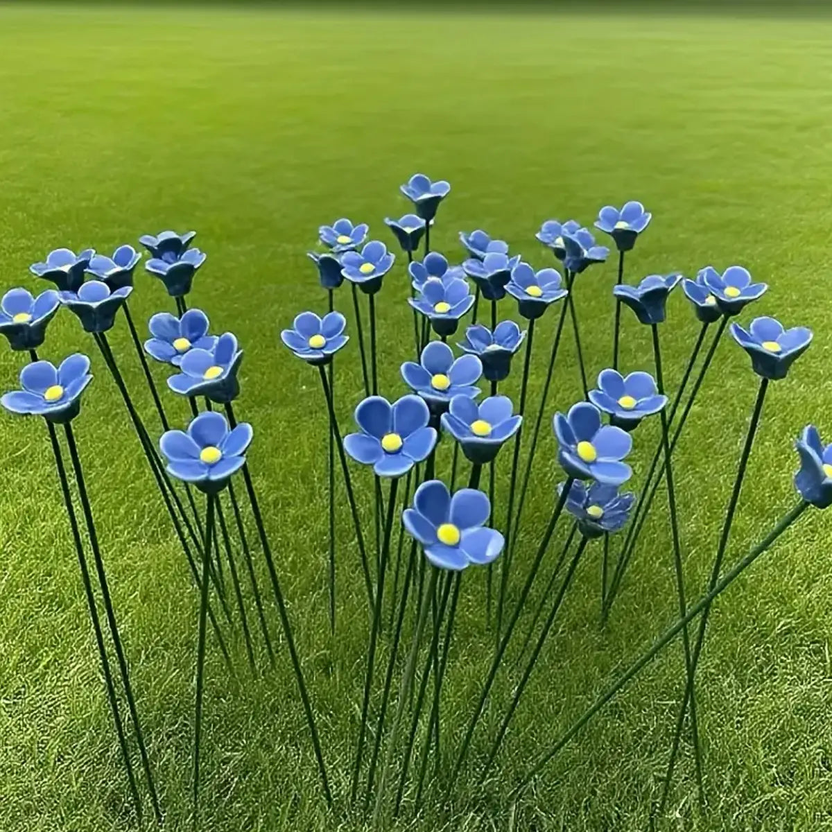 blue ceramic artificial flowers designed as forget me nots with yellow centers mounted on slender green stems ideal for decorating vases