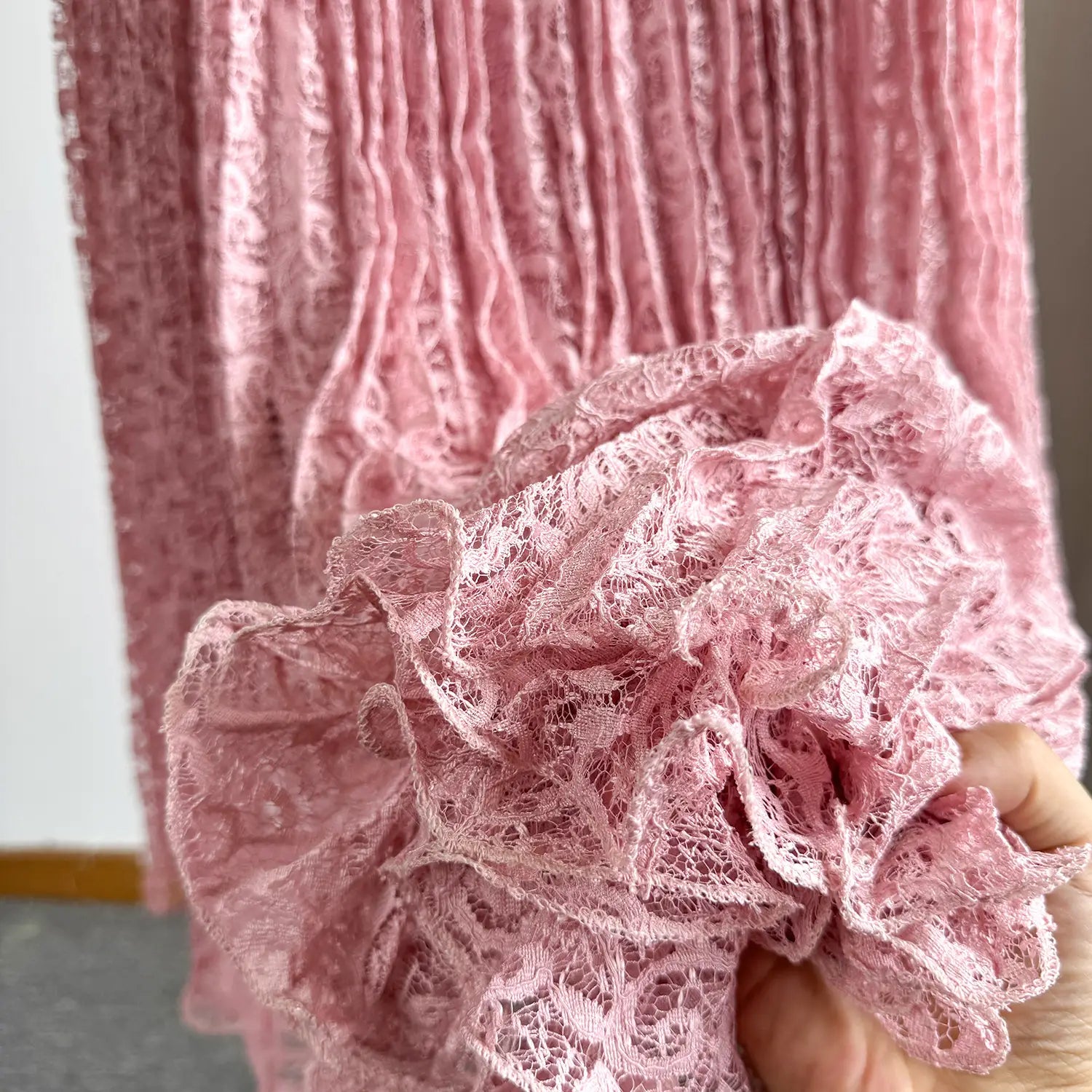A high waist pleated midi skirt in delicate pink lace with ruffles featuring intricate floral patterns and a soft flowing texture for Y2k streetwear.