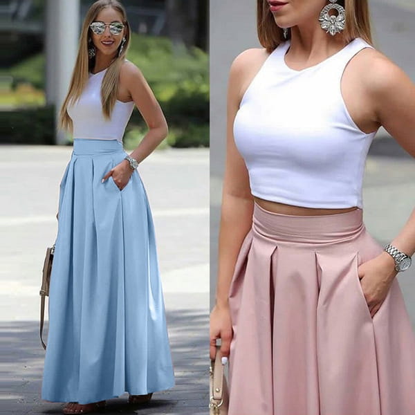 a white sleeveless crop top with a high neckline and fitted bodice paired with a pleated high waist maxi skirt