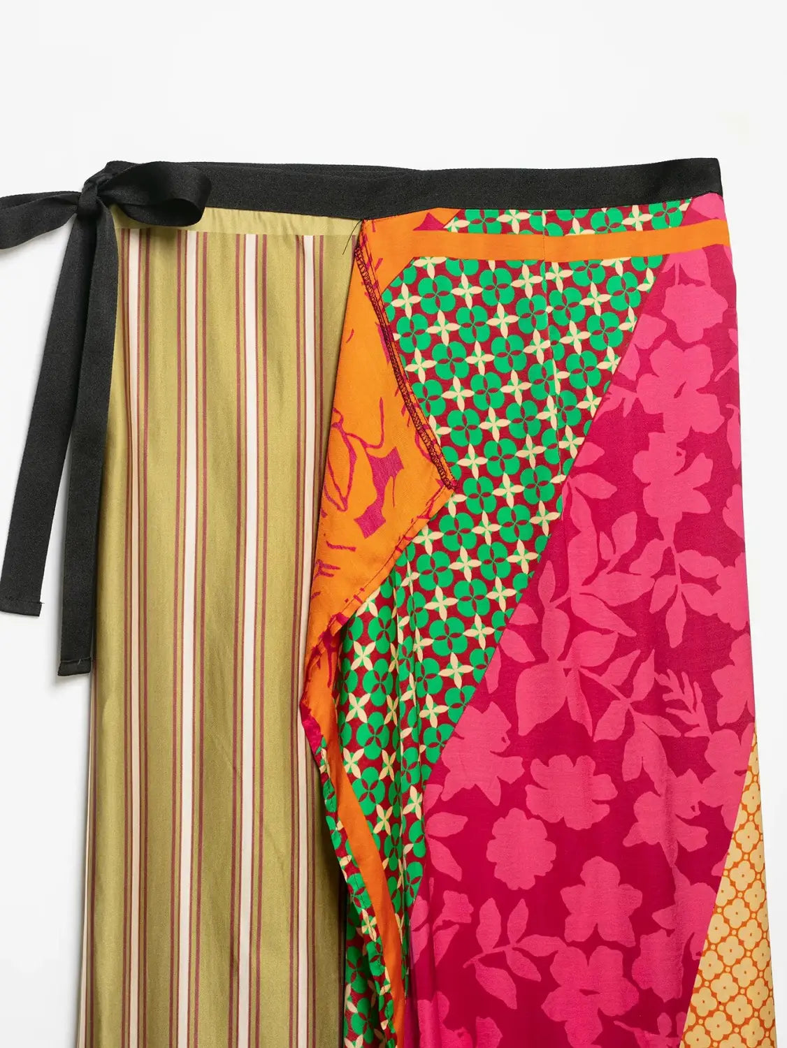 A vibrant floral print two piece midi skirt set featuring a patchwork wrap skirt with bold stripes green geometric patterns and pink floral prints in a flowing silk-like fabric.