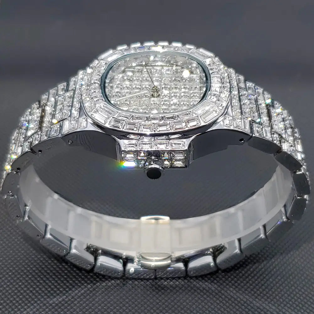 A dazzling iced out diamond quartz watch for men featuring a silver stainless steel band and bezel with a diamond grid pattern on the face.