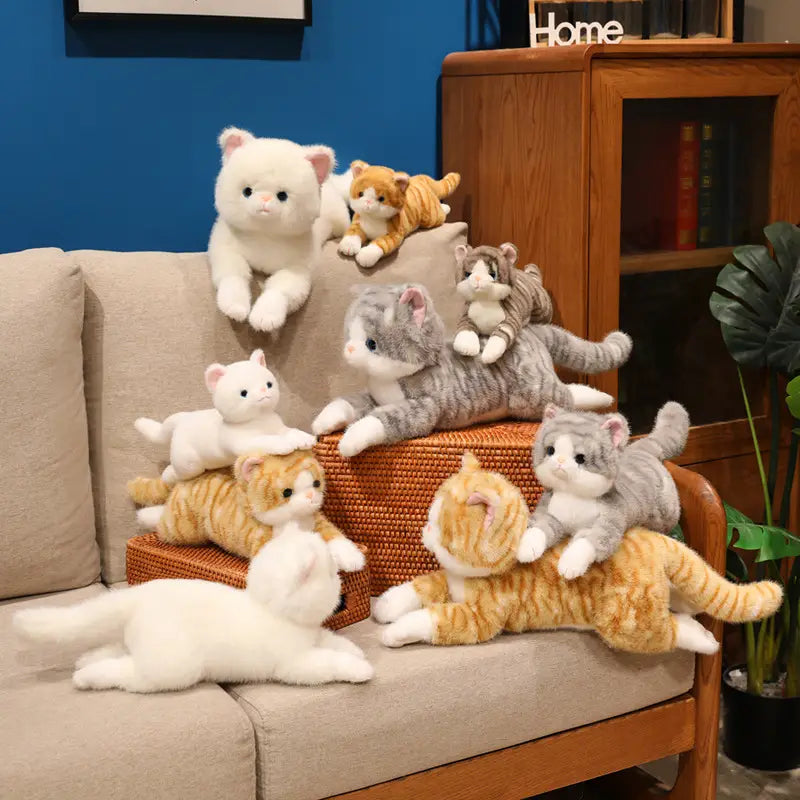 a collection of plush toys featuring soft cute kitten stuffed animals and pillows in white, orange tabby, gray tabby, and calico patterns