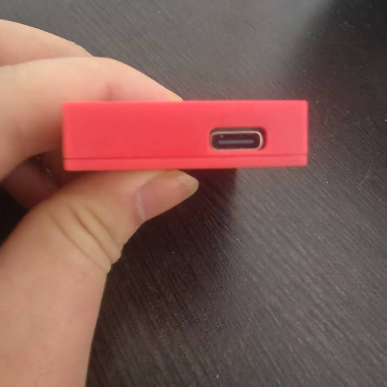 A red rectangular usb-c adapter held in hand paired with a pink game card storage box v2 accessory case for secure game card organization.