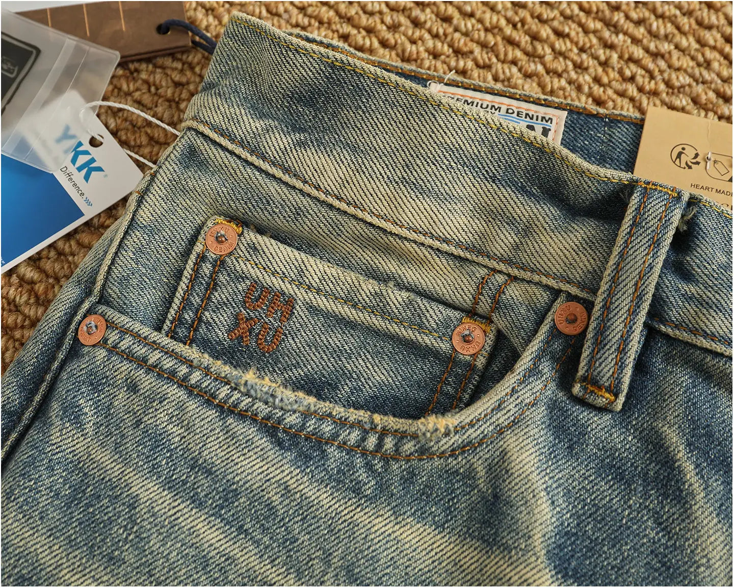 Distressed patchwork denim jeans men in blue denim with a faded wash copper-colored buttons and visible stitching details.