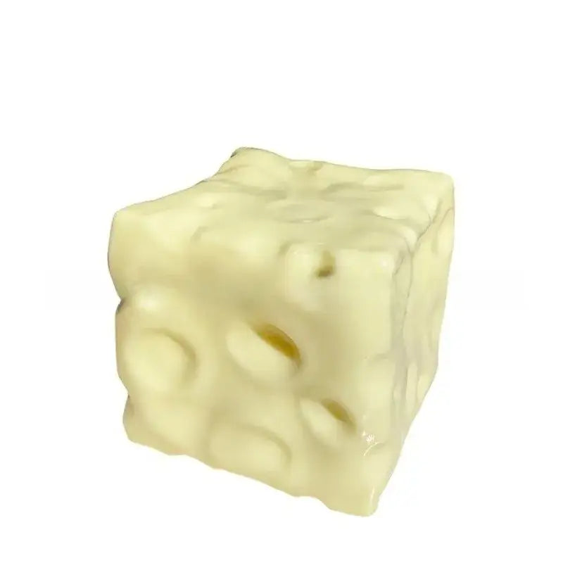 Cream-colored cube-shaped cheese block stress relief squeeze toy with characteristic holes and a slightly textured surface for stress relief.