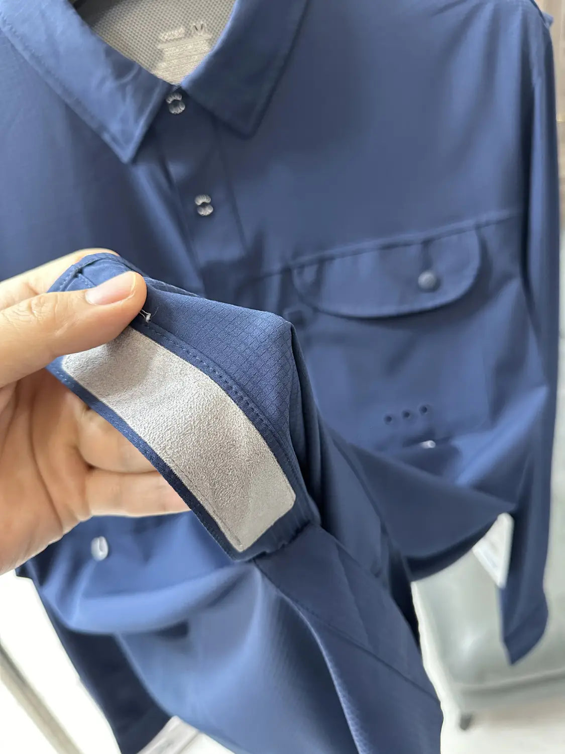 Men’s tactical outdoor long sleeve shirt in navy blue with a subtle sheen and a silver reflective strip along the cuff.