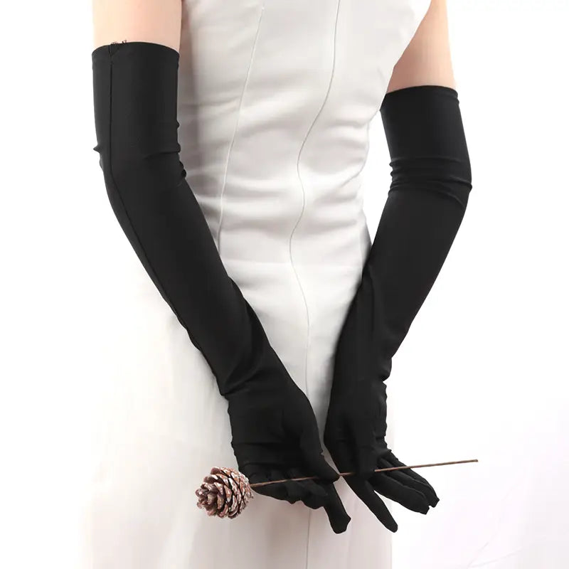 Guantes largos de ópera de satén negro para mujer, ceñidos con elegancia a los brazos y las manos de quien los lleva.