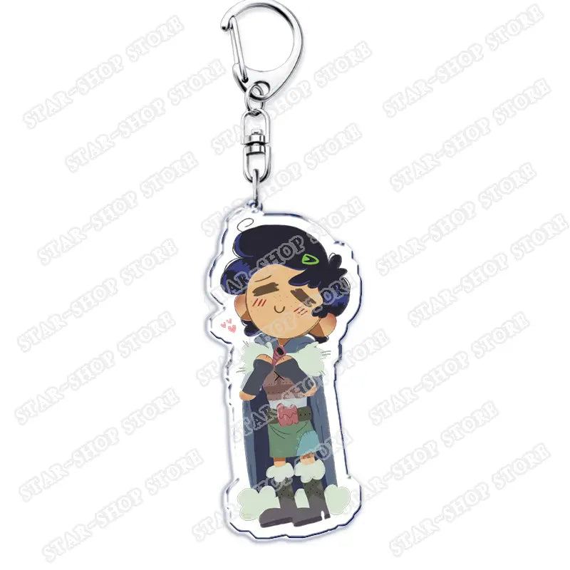 Clear acrylic Amphibia anime keychain featuring a chibi-style character with dark blue hair green eyes and cheerful expression dressed in layered clothing including a cape and boots.