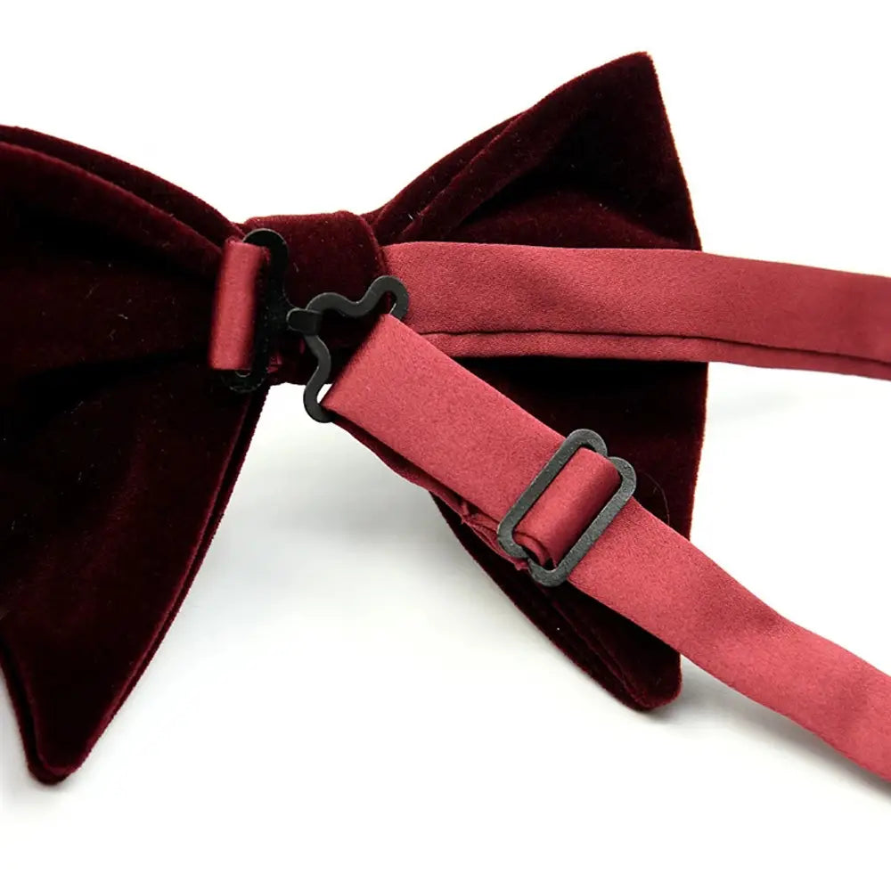 A rich burgundy velvet bow tie with matching satin straps and black metal clasps designed as formal neckwear and gift.