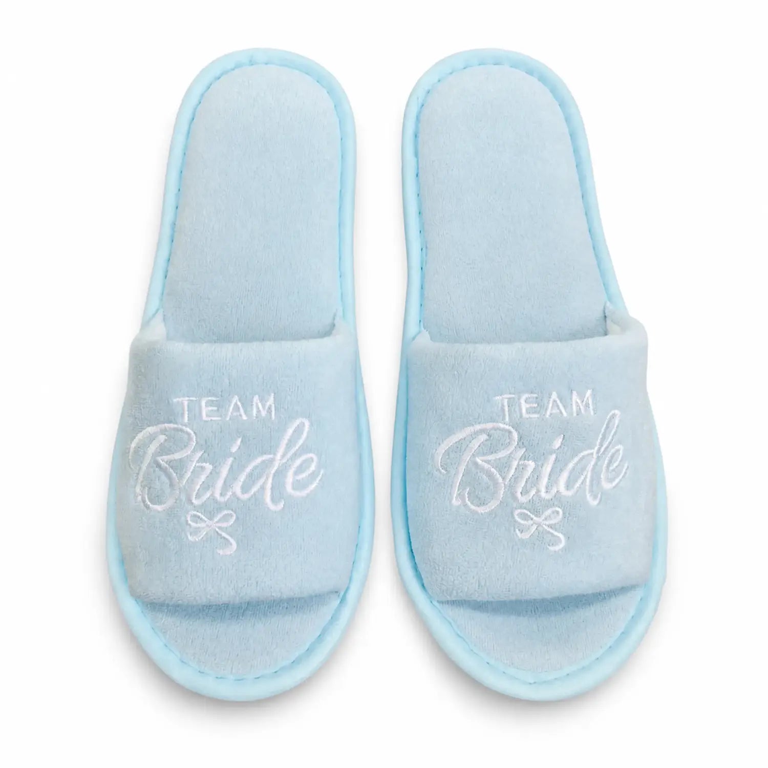 Mules de mariée à enfiler en peluche bleu clair pour l’équipe, avec la mariée brodée en écriture blanche et un petit nœud sous le texte.