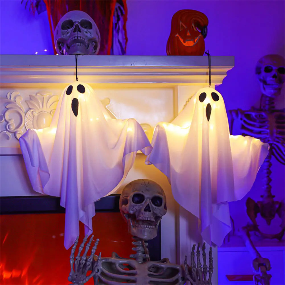 led hanging ghost halloween decoration features two glowing white ghost figures with black eye and mouth cutouts hanging from a mantel.