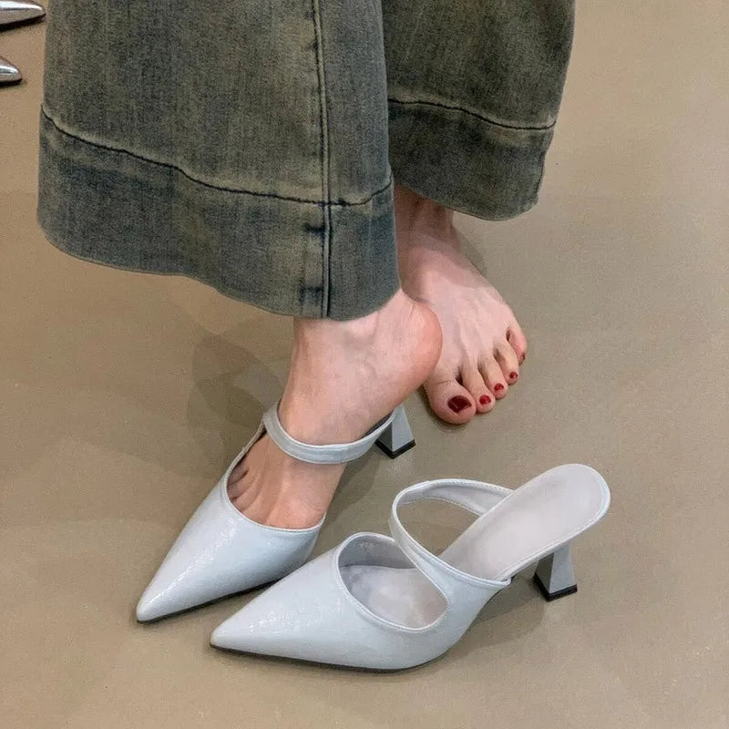 Mules en cuir noir à bout pointu présentant du cuir verni bleu clair avec un bout pointu épuré et une bride fine à la cheville.