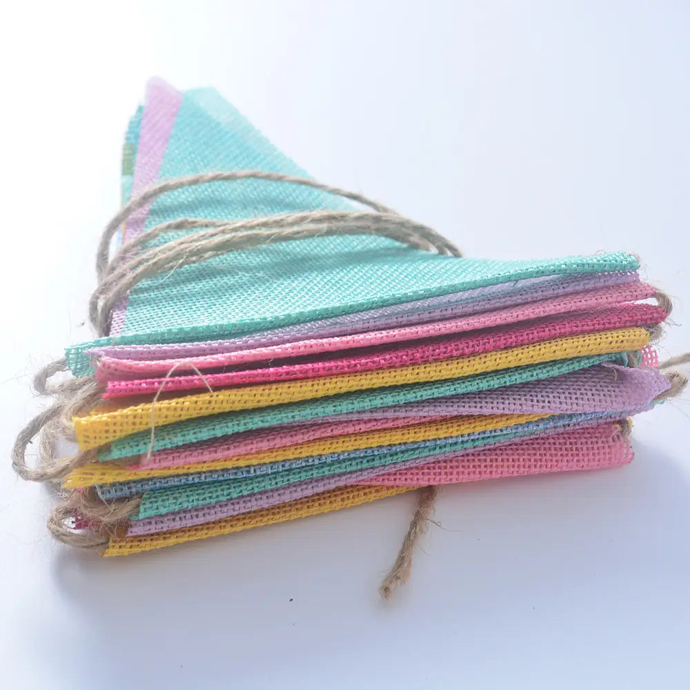 Décoration de guirlande de fête en feutrine pastel, présentant une guirlande de fanions en toile de jute aux couleurs pastel, avec des liens en ficelle naturelle.