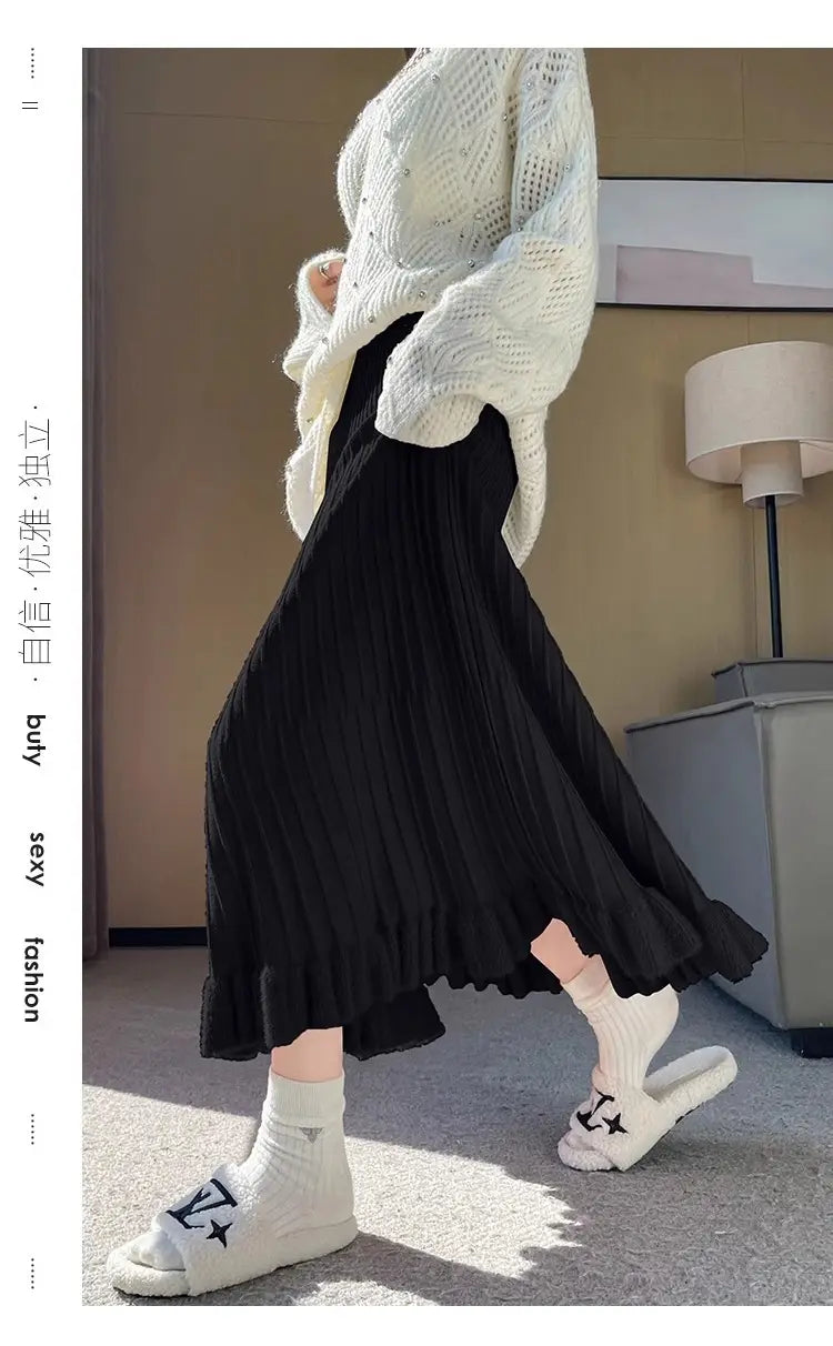 Jupe mi-longue en maille noire, à taille haute, design plissé et ourlet volanté fluide.
