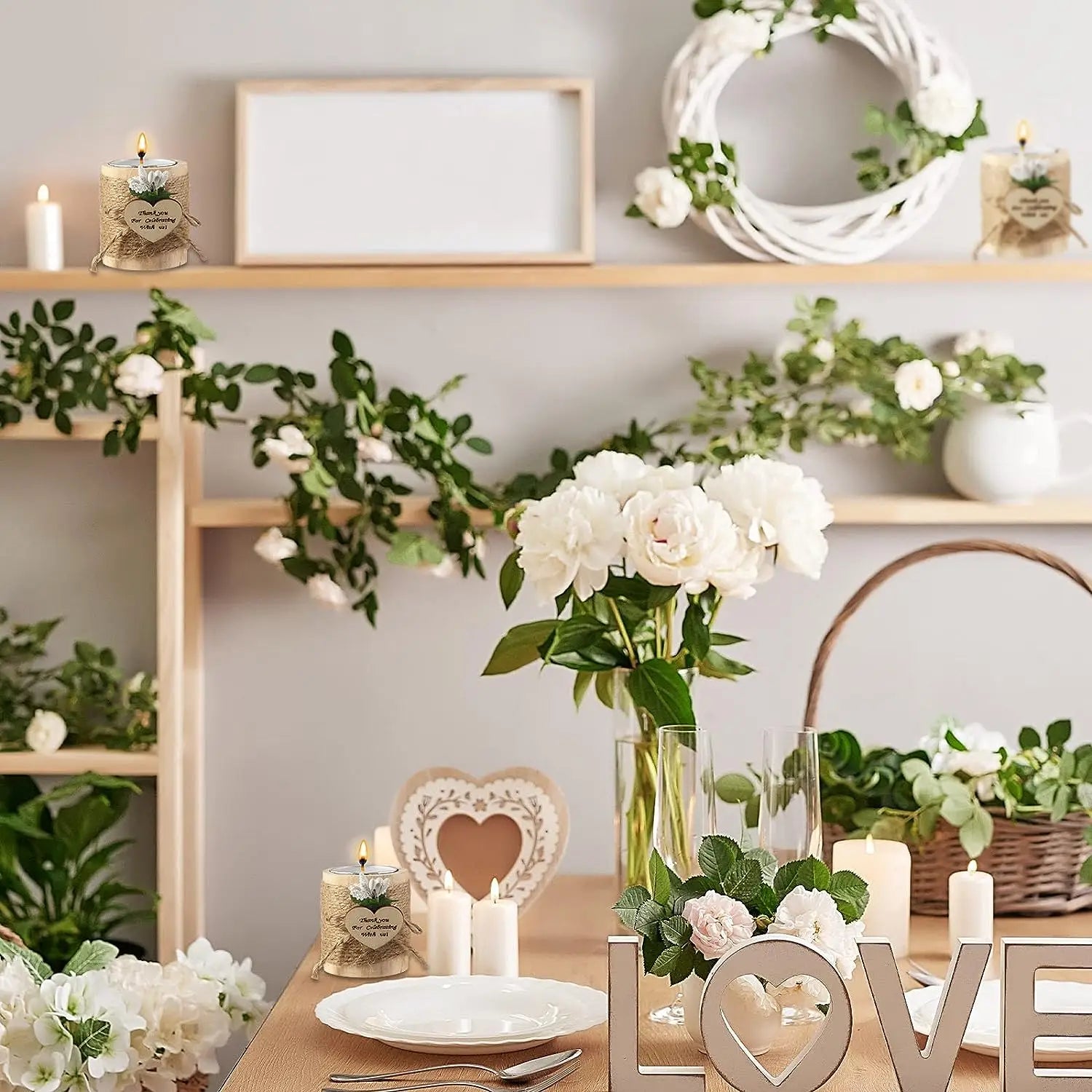 Des bougeoirs en bois pour petites bougies chauffe-plat, en tant que cadeaux d’invités de mariage, présentés à côté d’un vase en céramique blanc contenant un bouquet de pivoines blanches aux feuilles vertes.