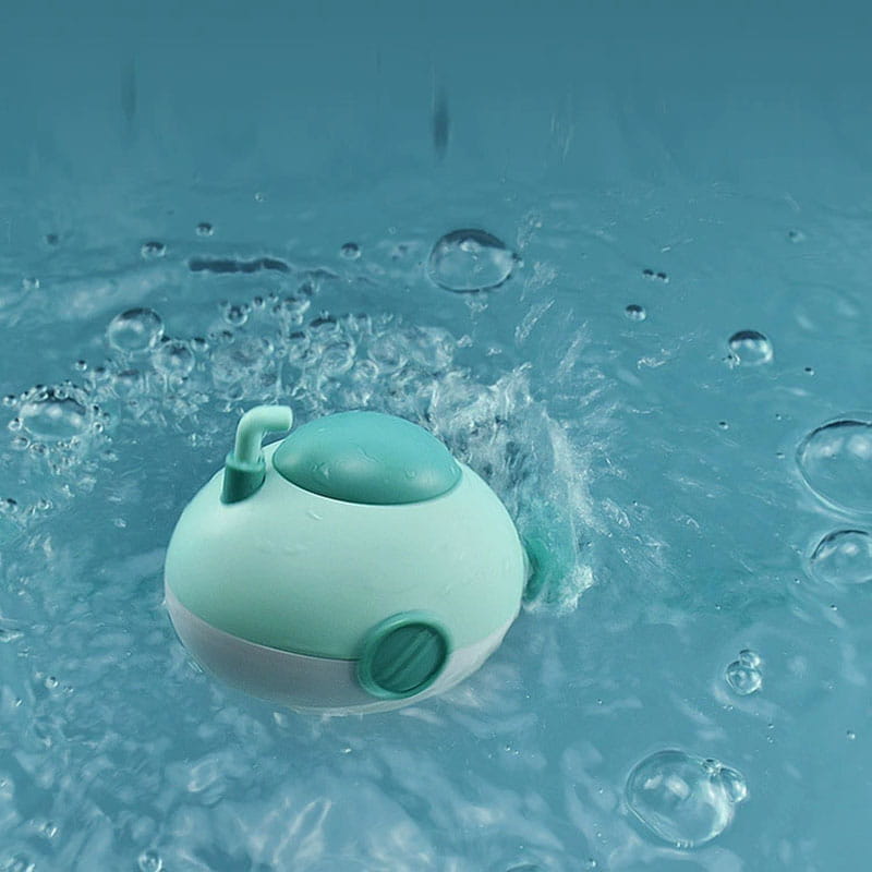 Ein minzgrünes und weißes Kunststoff-U-Boot-Bade-Spielzeug für Babys mit einem kleinen Rohr oben, das im Wasser schwimmt.