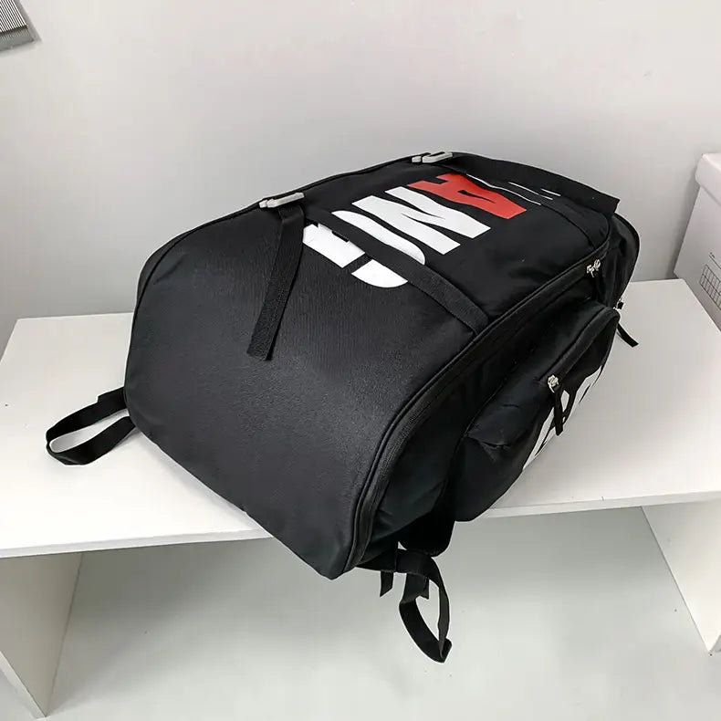Black waterproof gym backpack and travel duffel bag with bold white and red lettering on the front.
