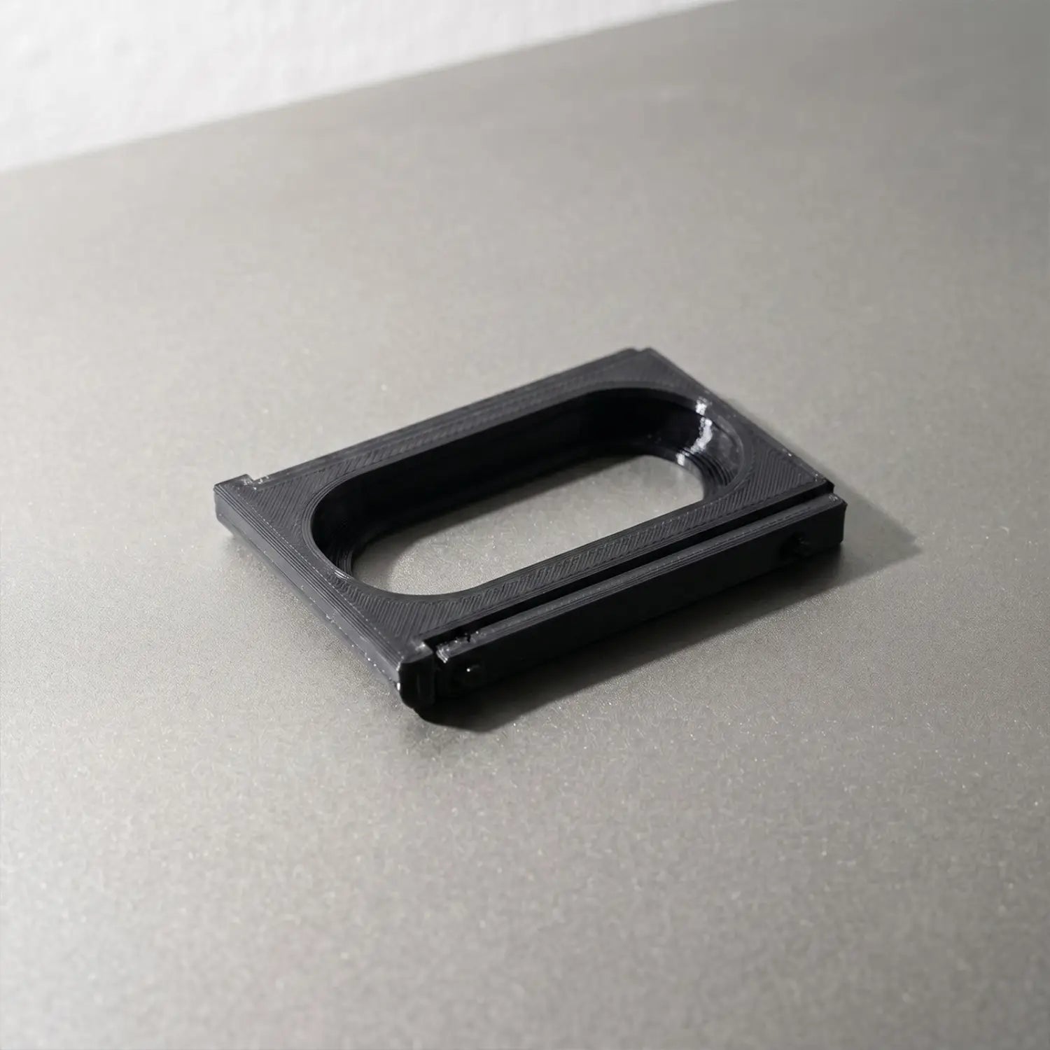 black rectangular 3d-printed adapter bracket frame for fitbit air to whoop 5.0 with a central oval cutout and visible layer lines