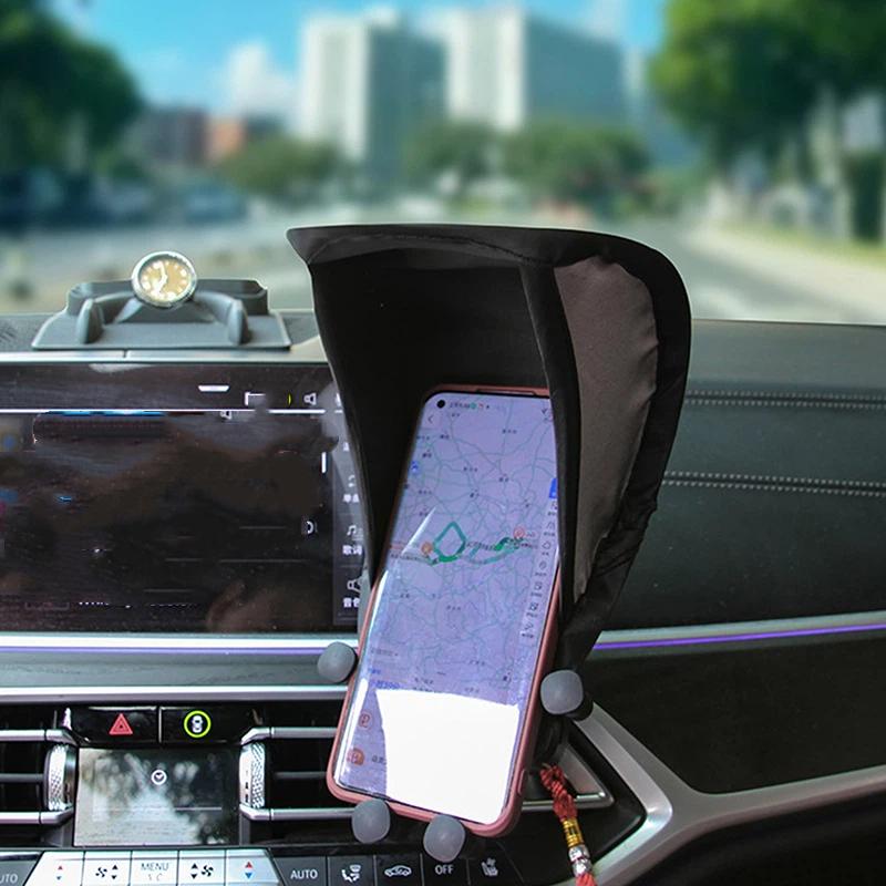 schwarze Stoff-Telefonhalterung mit verstellbaren Silikongriffen, die ein Smartphone auf dem Armaturenbrett im Fahrzeug hält, für ein Telefon-Sonnenblendengehäuse mit Anti-Blend-Plattenabdeckung.