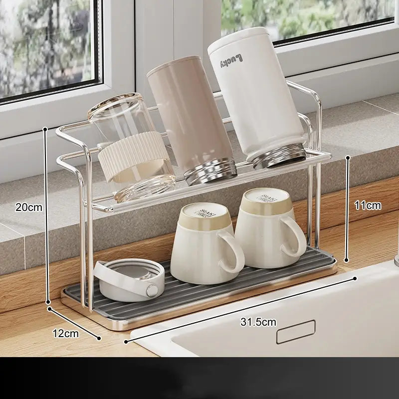 Silver stainless steel two-tier mug and cup storage rack with a gray rubberized mat base and wooden trim.