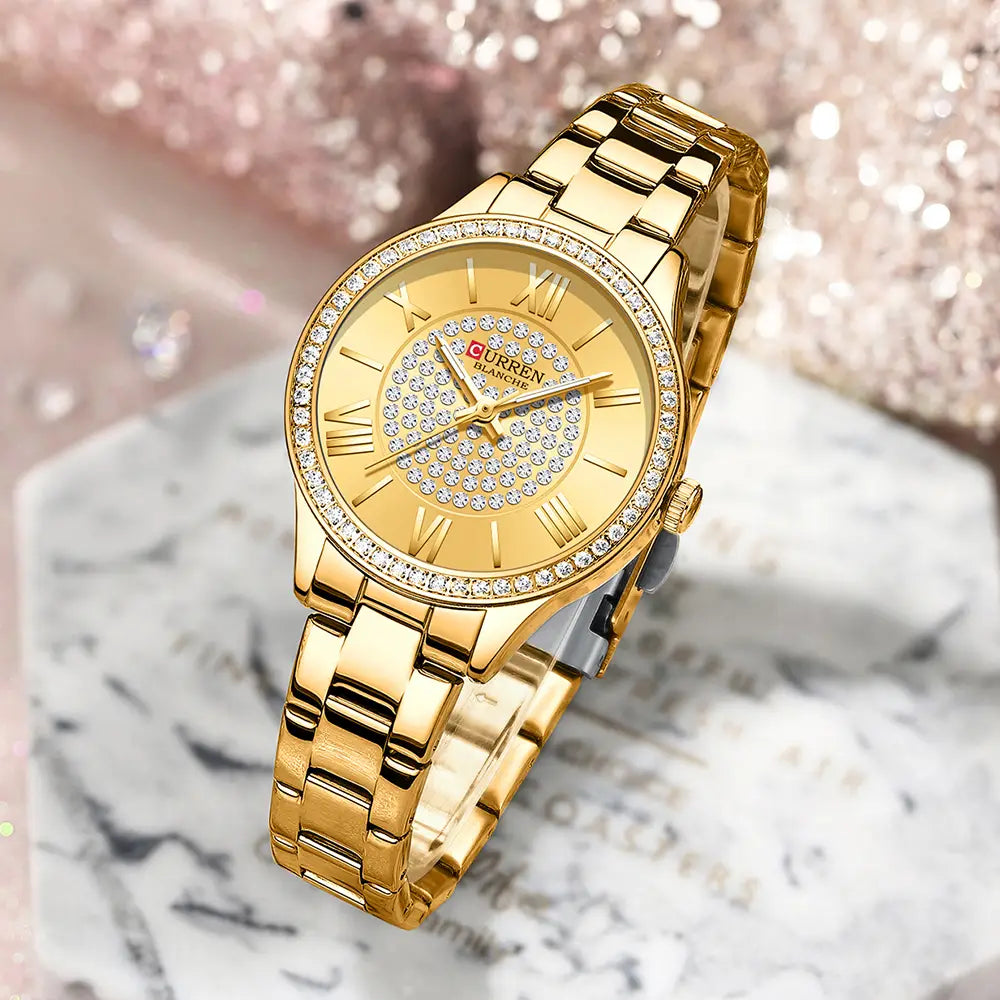 Gold-tone stainless steel Curren women quartz wristwatch with diamond-encrusted bezel and face featuring roman numerals.