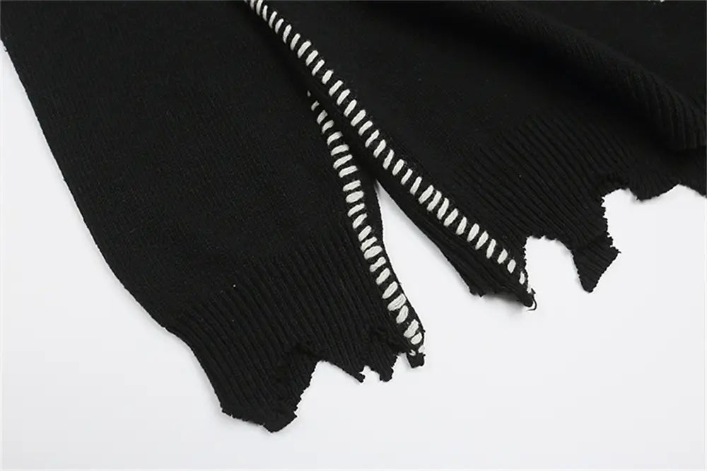 sin刺繍のブラックのオーバーサイズニットセーターからの、ほつれたエッジとコントラストの白いジグザグステッチが特徴のブラックニットの袖。