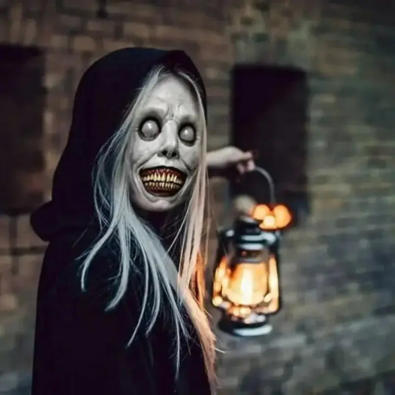 A creepy Halloween resin horror mask featuring a full face grotesque design with pale long hair and a black hooded costume accessory.