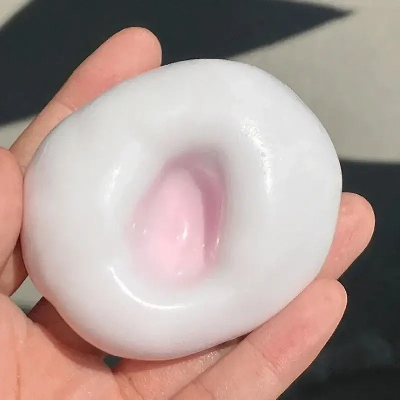 Ein durchscheinender, weißer, glänzender Stressball mit einem weichen rosa Zentrum, gehalten in einer Hand – ein Fidget-Spielzeug mit knisternder Textur.