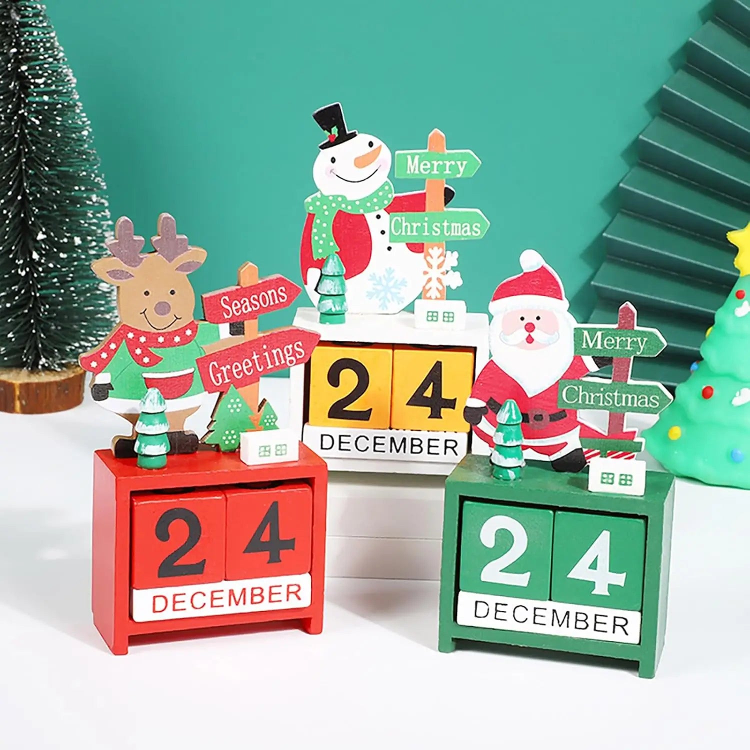 Wooden Christmas countdown calendar blocks in red and green featuring festive snowman reindeer and Santa figurines on top.