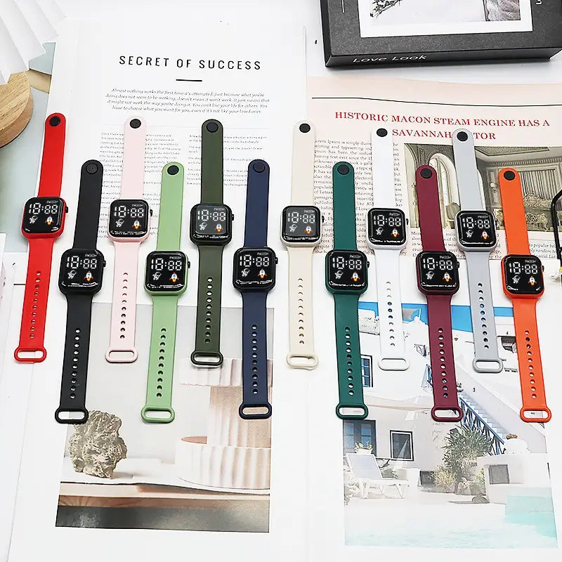 Une collection de montres électroniques sport numériques colorées pour enfants, garçons et filles, avec affichages LED et bracelets en silicone en rouge, noir, rose, vert, bleu marine, blanc, bordeaux et orange