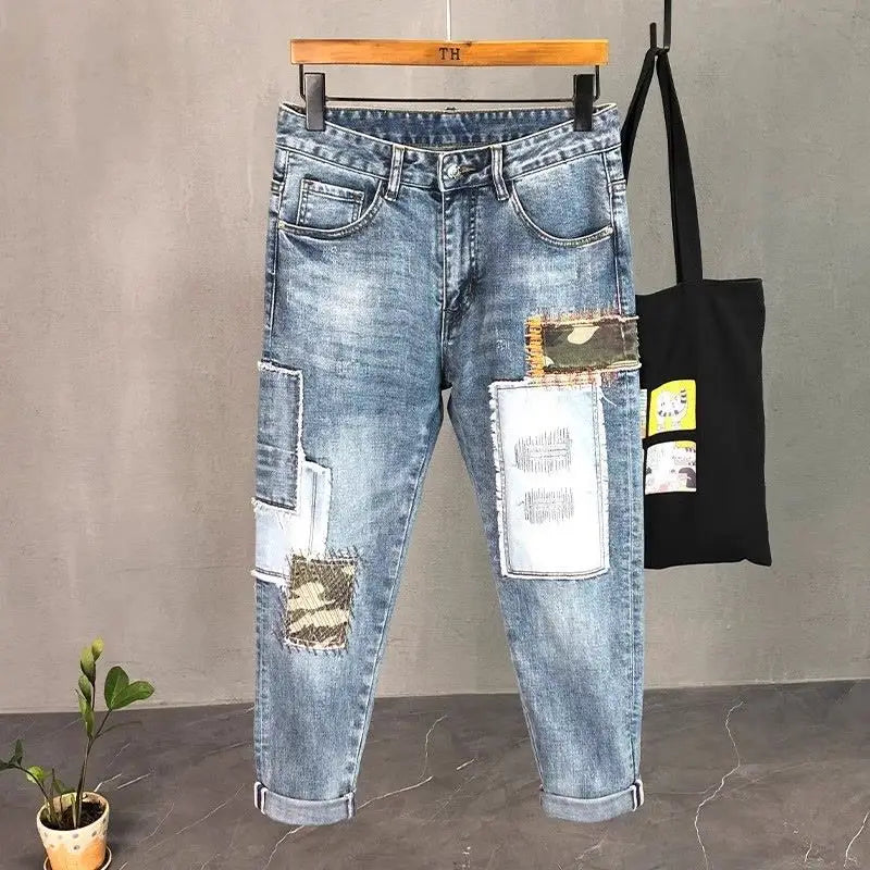 Distressed slim fit light wash denim jeans featuring distressed patches and camouflage fabric accents.