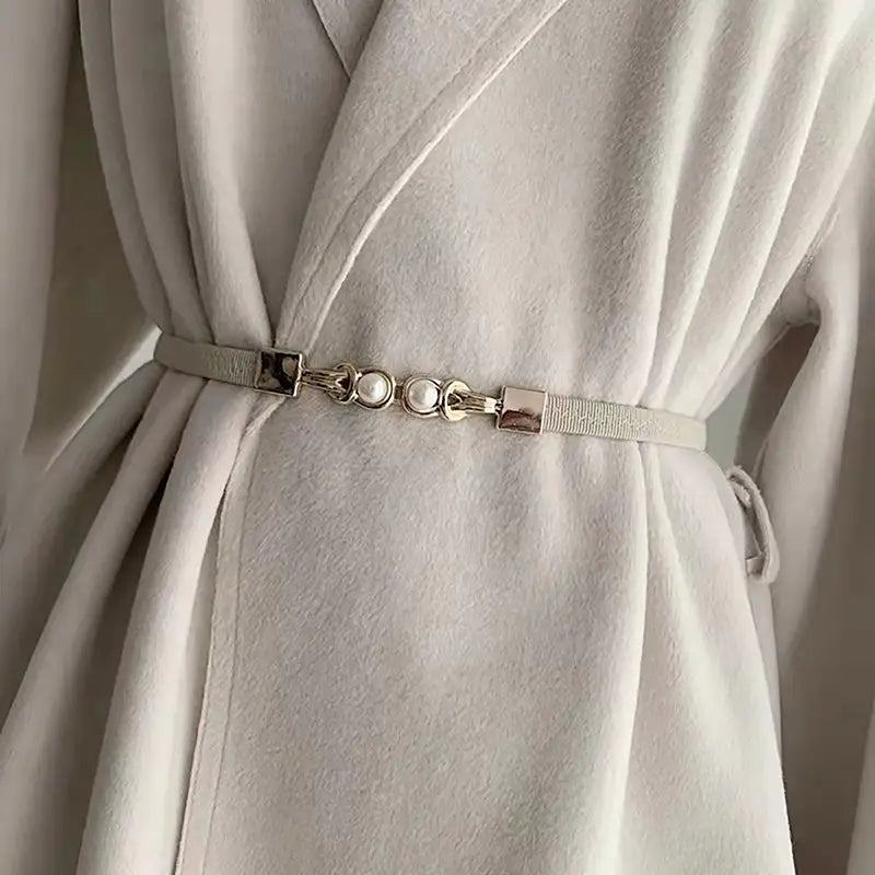 Ein zarter silberfarbener Perlen-Schnallen-Taillegürtel für Damen mit einem strukturierten Stoffriemen und drei perlenähnlichen Zierelementen mit rechteckigen Metallverschlüssen.
