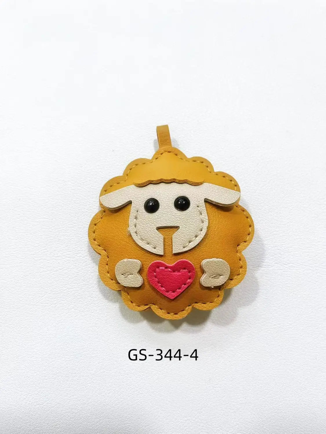 A charming mustard-yellow leather sheep keychain with a white face, black eyes, beige paws, and a red heart stitched on its chest used as a cute animal bag charm.