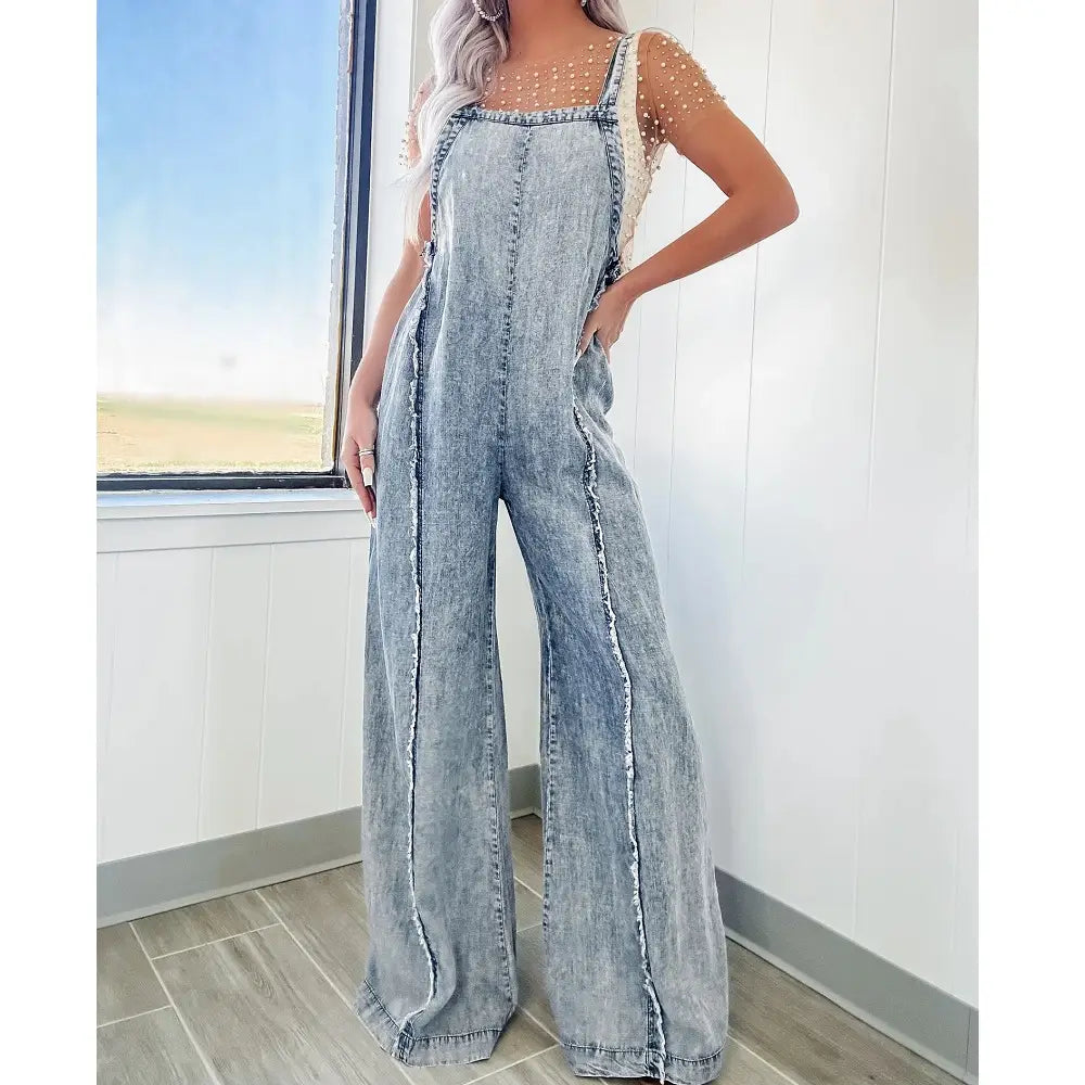light-wash denim overalls with frayed edges and a wide-leg cut in a vintage long jumpsuit style for women