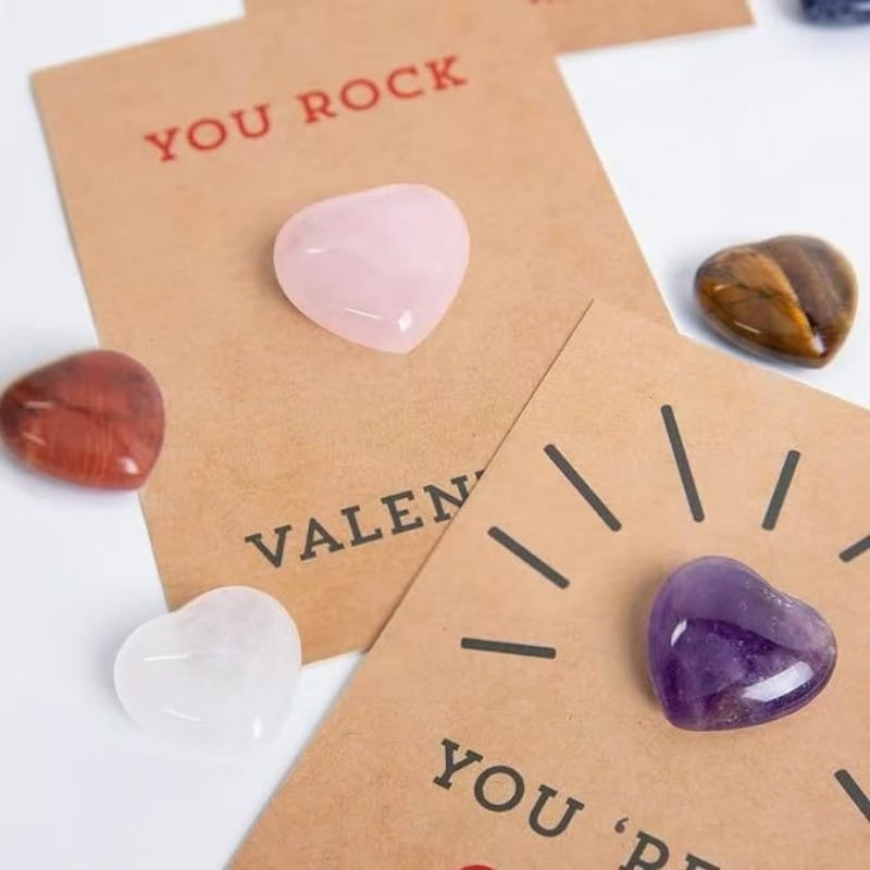 A translucent pink heart-shaped crystal stone gemstone heart valentine card displayed on a brown card with you rock printed in red.