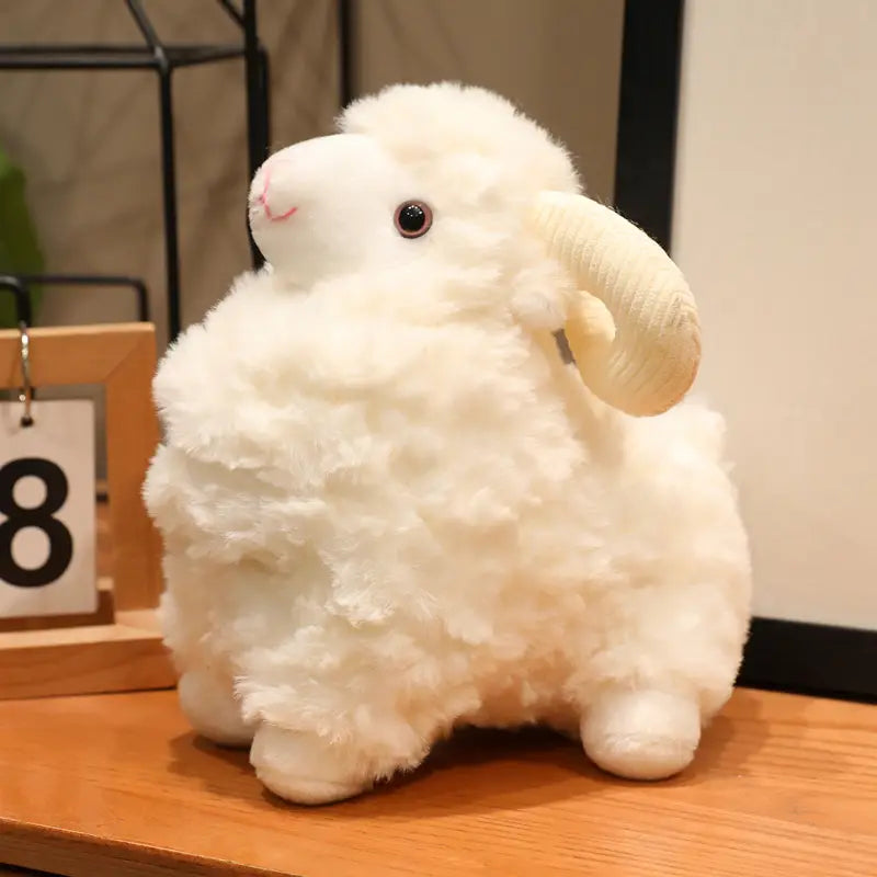 Plüschschaf-Geschmacktier mit einer flauschigen weißen weichen Puppe mit lockiger wolleartiger Textur und cremefarbenen geschwungenen Hörnern.