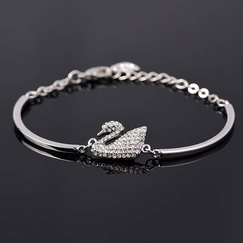 Bracelet jonc en argent avec breloque de cygne, présentant un motif de cristaux pavés sur une lanière en argent poli.