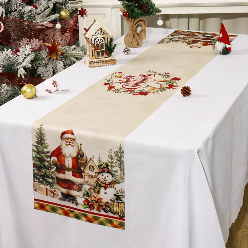 Beiger, weihnachtlich thematischer Tischläufer mit einem bedruckten Design von Santa Claus und einem Schneemann mit festlichen Holiday-Elementen im rustikalen Landhausstil.