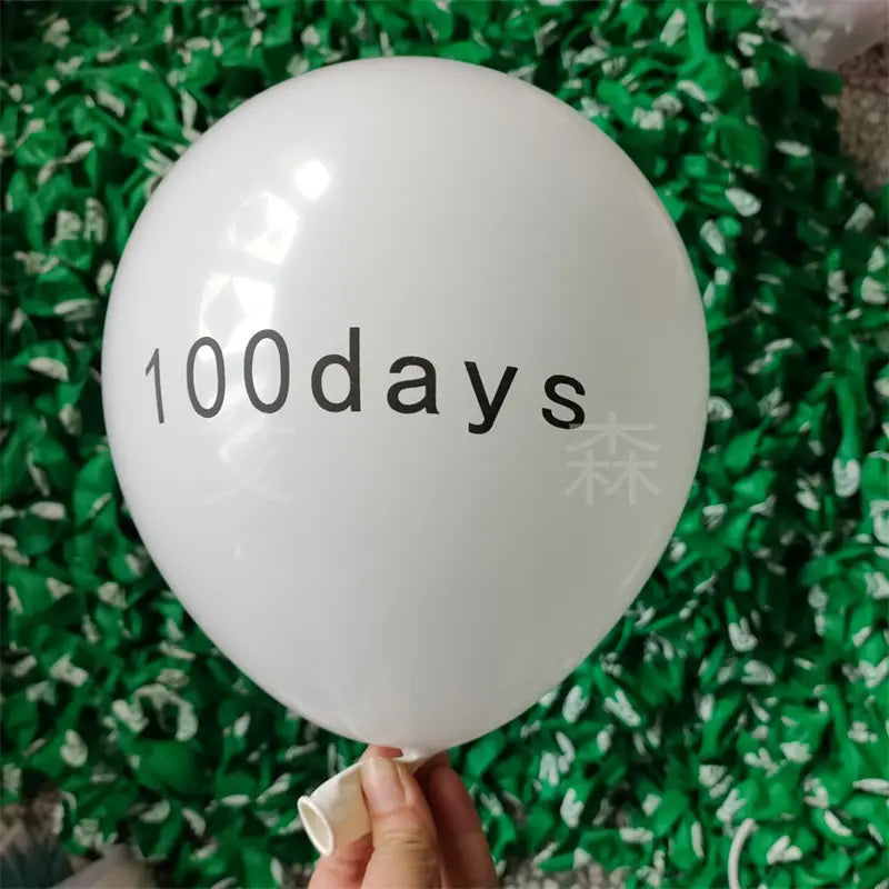 un ballon d’anniversaire en latex blanc lisse avec « 100days » imprimé en noir, dans un lot assorti de 20 ballons en latex d’anniversaire imprimés.