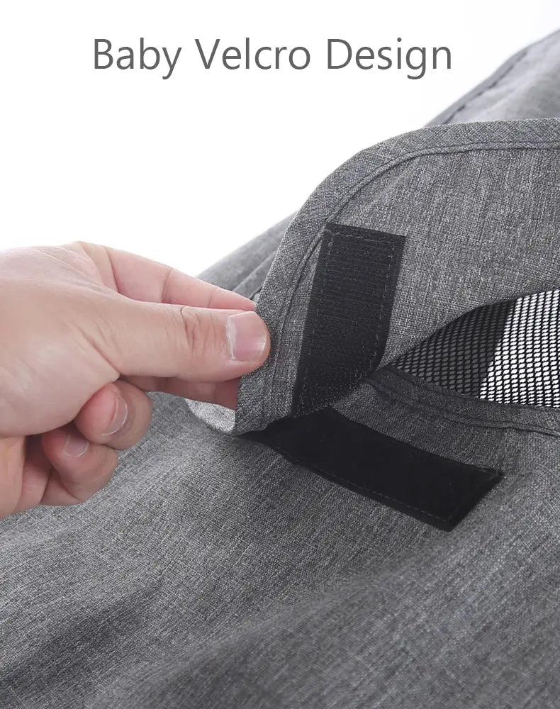 Graues meliertes Gewebe mit schwarzen Klettstreifen auf der Rückseite eines universellen Sonnensegels für Kinderwagen mit UV-Schutz, ausgelegt für eine kinderfreundliche Verwendung.