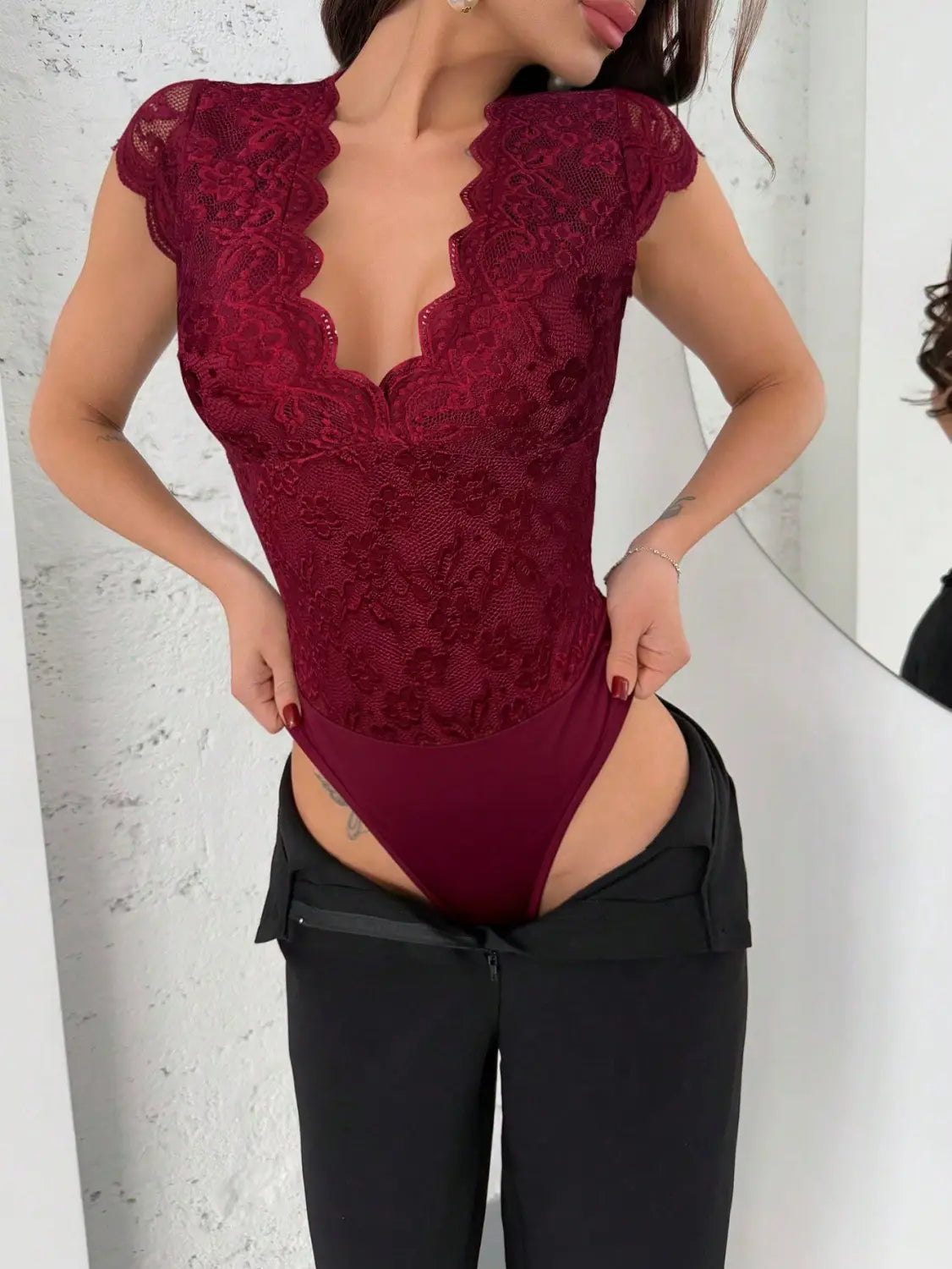 A deep red lace v-neck bodysuit featuring a scalloped neckline and cap sleeves.