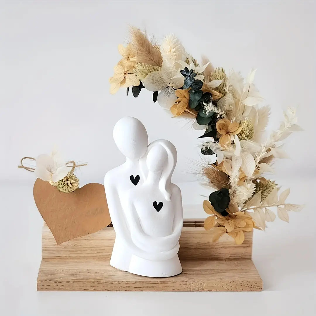 Statuette de couple en céramique blanche avec deux autocollants en forme de cœur noirs, présentée comme un moule à bougie en silicone 3D où le couple s’embrasse.