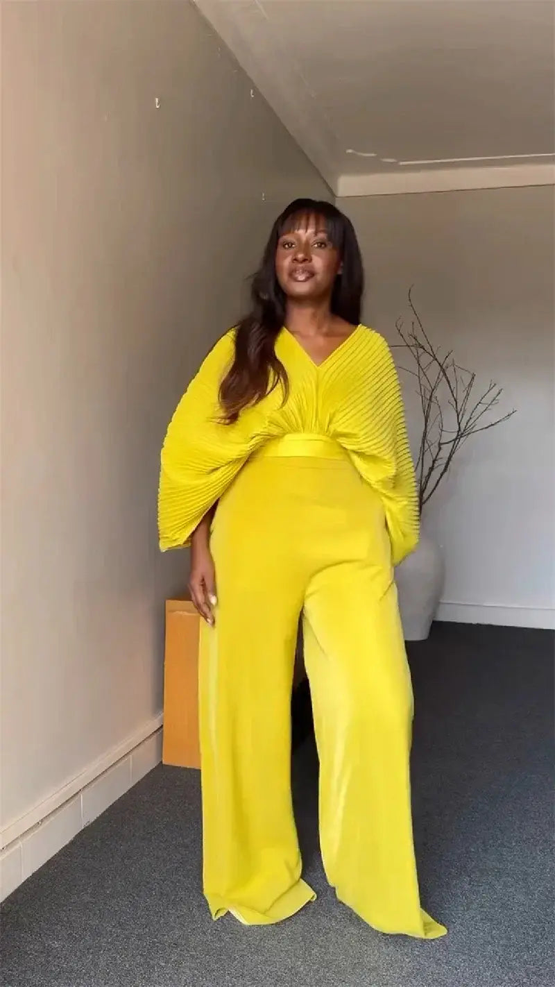 bright yellow velvet jumpsuit with voluminous ribbed long sleeves and cinched waist paired with purple satin two piece set wide leg pants.