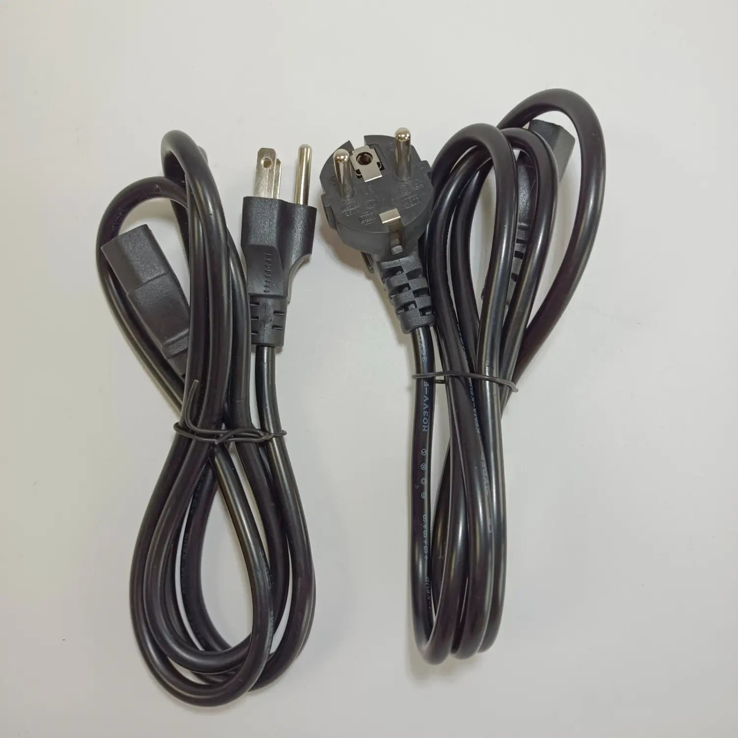 black power cords with two flat prongs and a three-prong european-style plug coiled neatly for fiber fusion splicer charger used with signal fire in mainland china