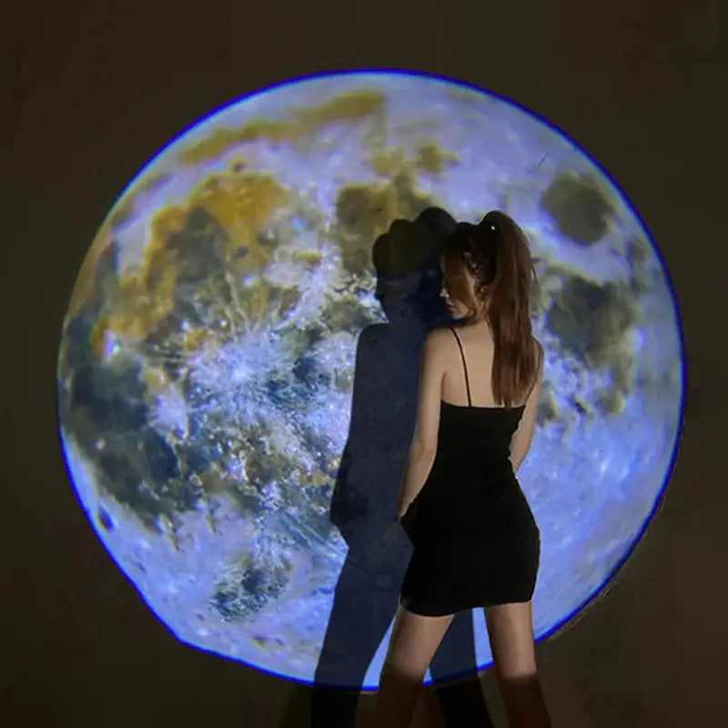 Una mujer con un mini vestido negro sin tirantes se encuentra frente a una gran lámpara de proyección que muestra una imagen detallada de la luna para la luz de estrellas de galaxia USB de luna y Tierra.