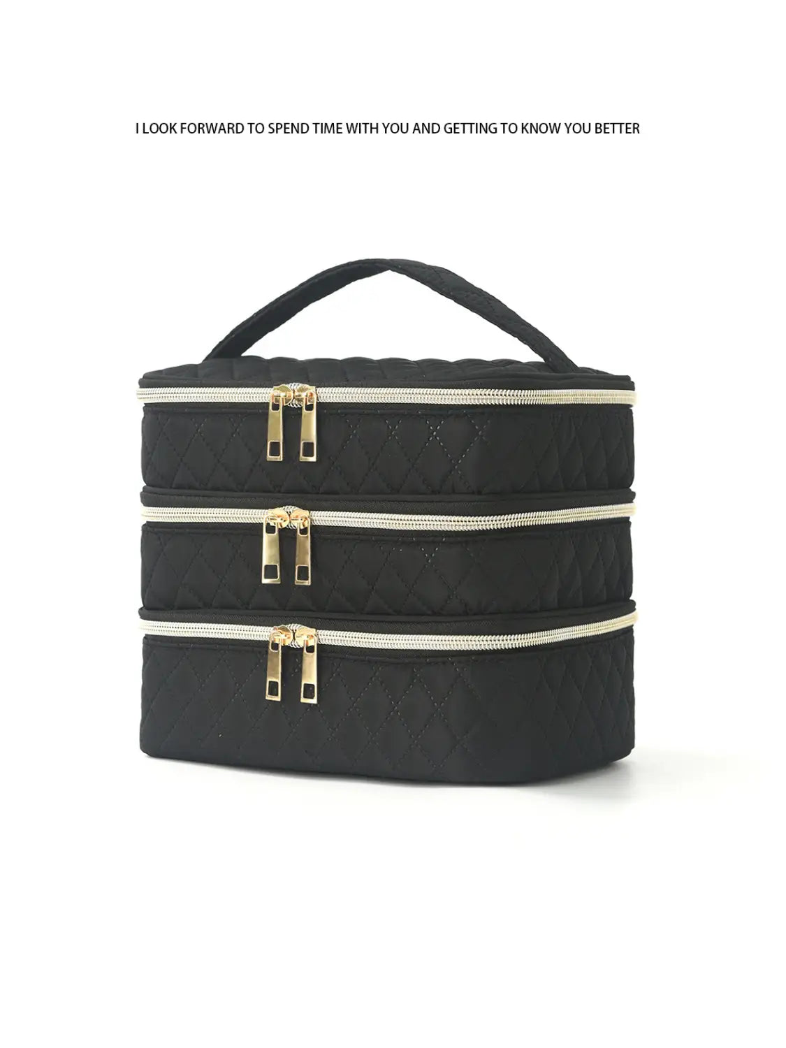 Bolsa de almuerzo negra acolchada en tres compartimentos con cremalleras de tono dorado y asa superior, diseñada como estuche de maquillaje de viaje.